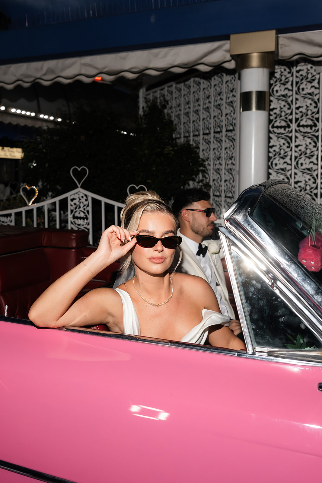Bride and groom posing in the pink Cadillac at a Little White Wedding Chapel for their classy elopement in Vegas.