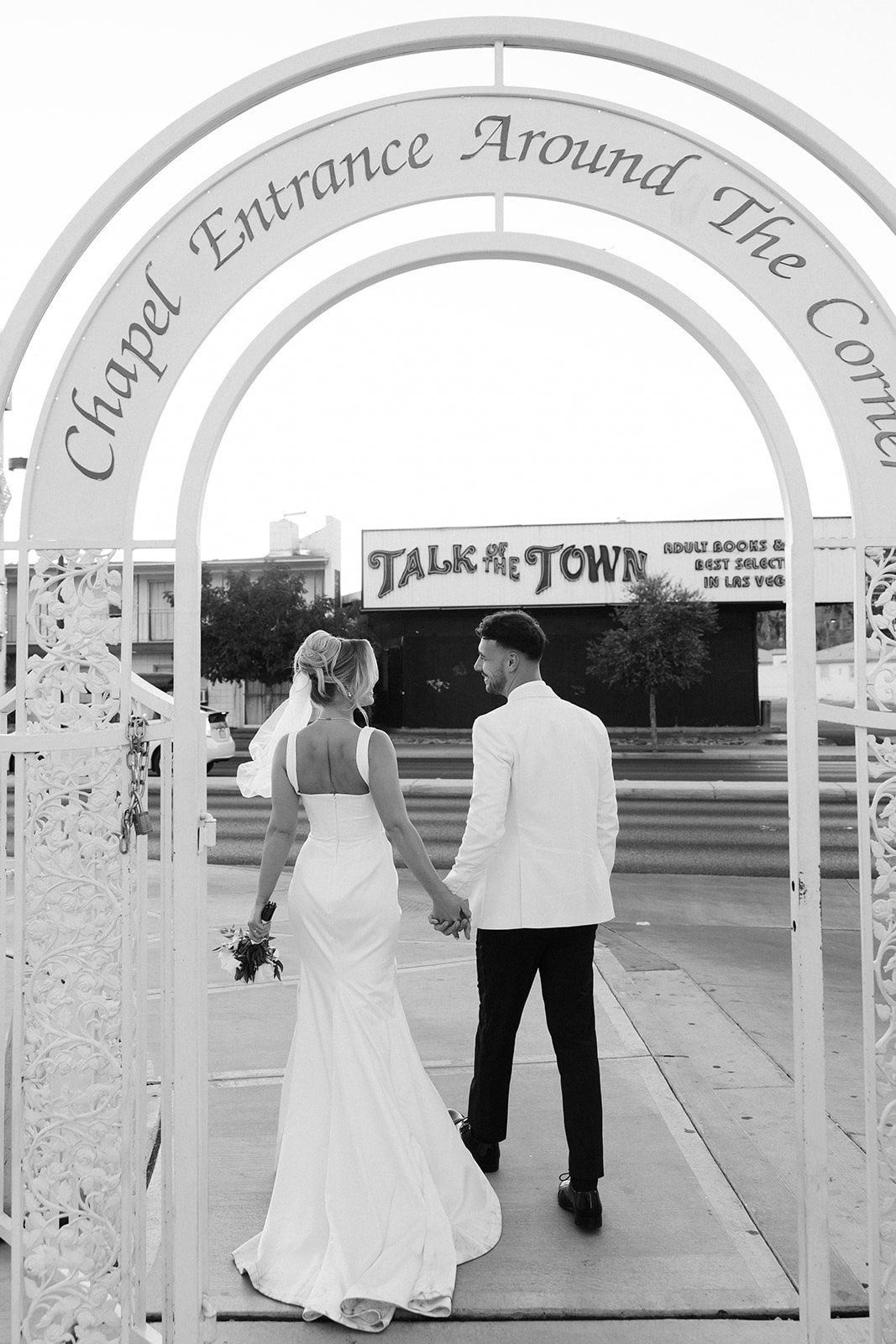 Black and white photo of a bride and groom walking outside of a Little White Chapel for their classy elopement in Vegas.