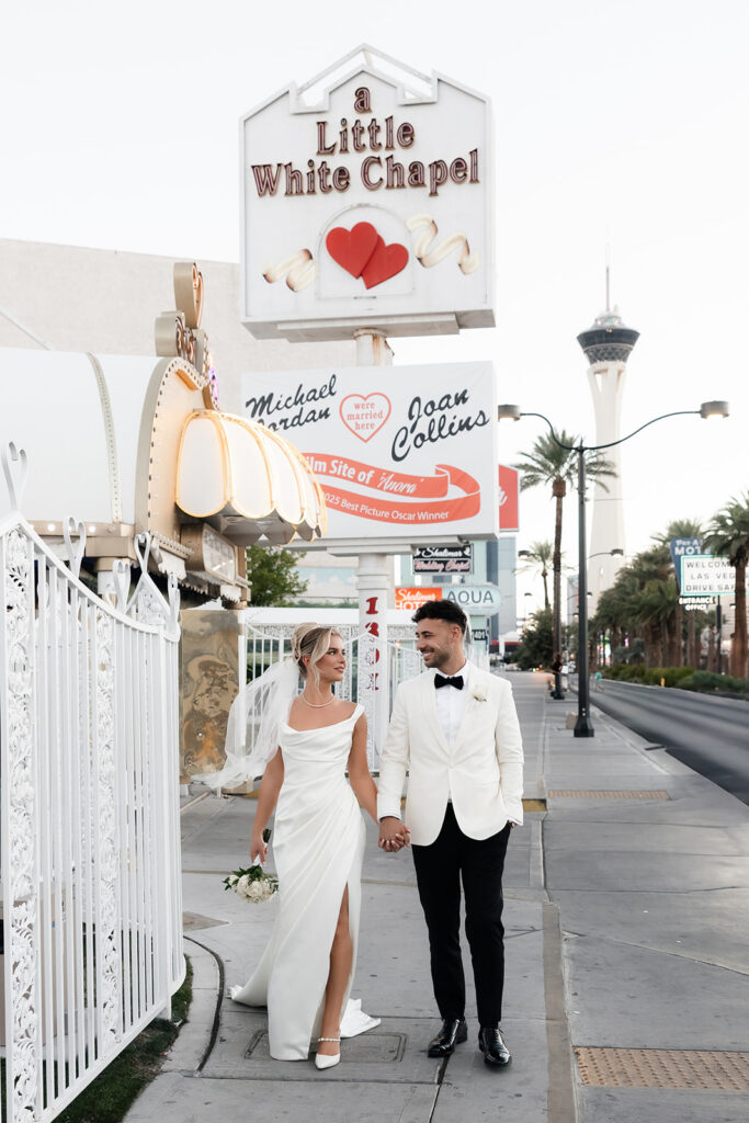 Bride and groom walking in front of a Little White Chapel in Las Vegas.