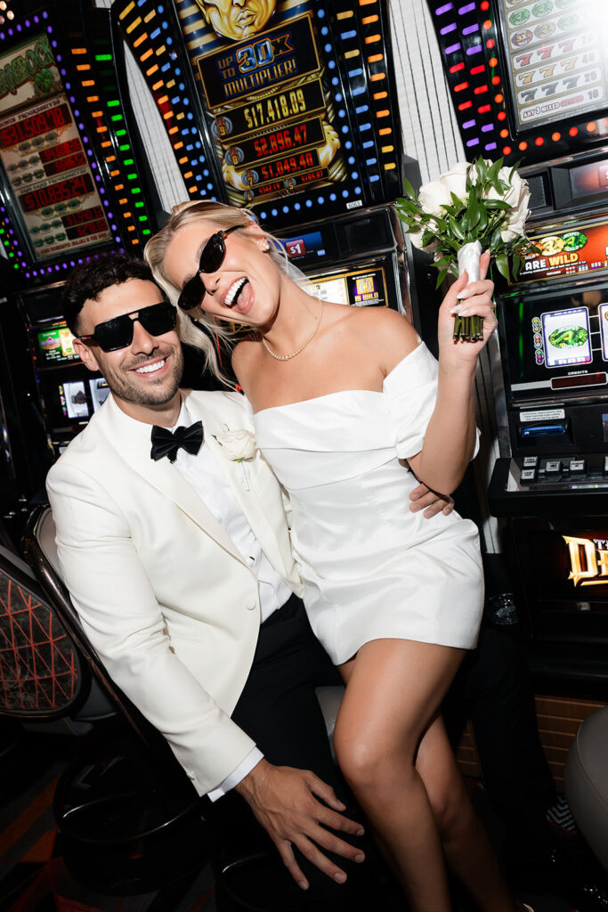 Bride and groom laughing together during casino portraits as part of their classy elopement in Vegas.
