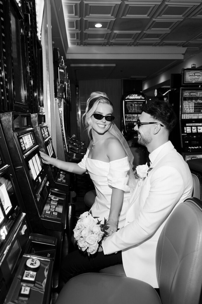 Black and white photo of a bride and groom playing slots on Fremont Street in Las Vegas.
