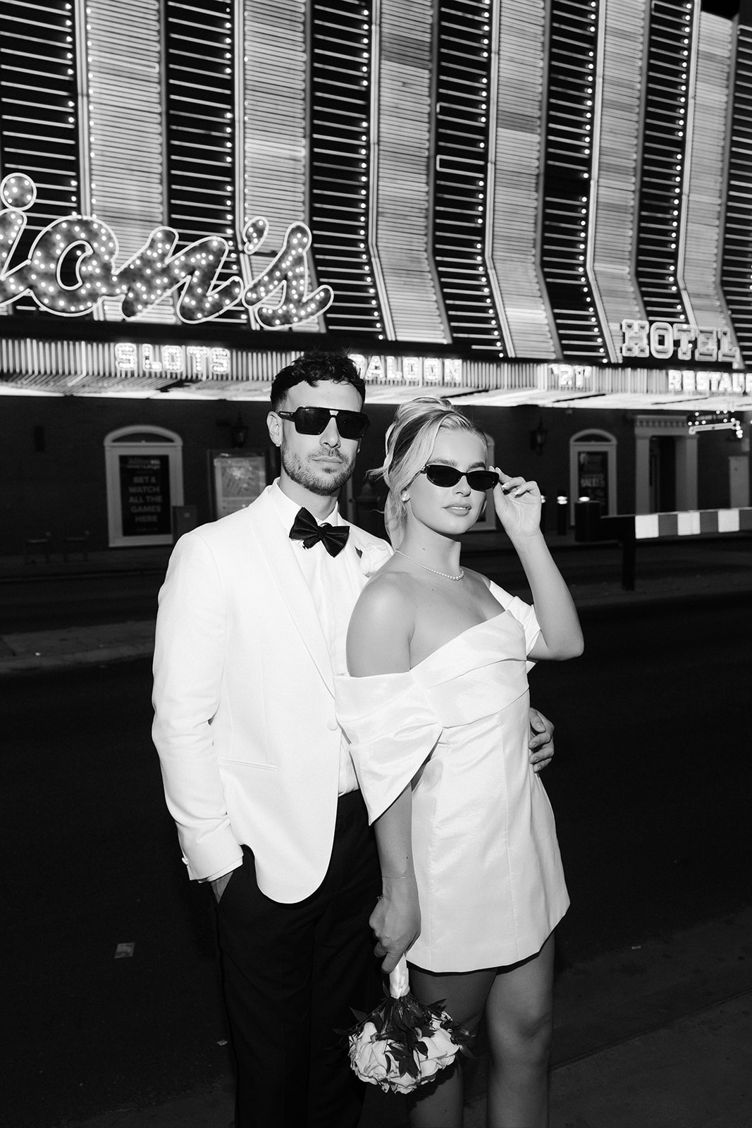 Black and white flash photo of a bride and groom posing outside of Binion's in Las Vegas.
