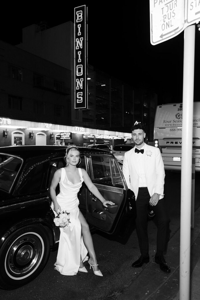 Couple posing beside a vintage Rolls Royce from Royal Rides with Binion’s neon sign glowing behind them in Las Vegas.