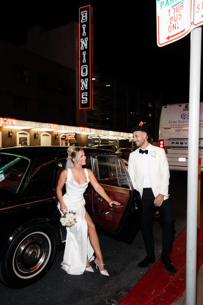 Couple posing with vintage Rolls Royce from Royal Rides on Fremont Street at night during their classy Vegas elopement.