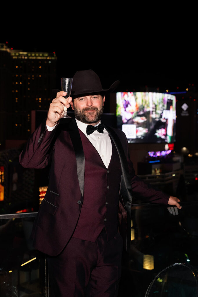 Guest raising a champagne glass in celebration during the Boulevard Pool Deck ceremony at a Cosmopolitan wedding in Las Vegas.