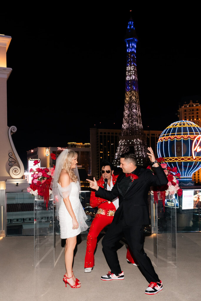 Groom dancing beside an Elvis impersonator as the bride watches during their Cosmopolitan wedding ceremony.