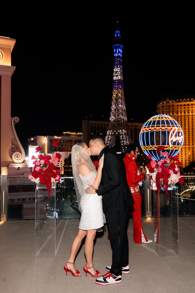 Bride and groom sharing a kiss at the altar with the Las Vegas Strip behind them during a Cosmopolitan wedding ceremony.