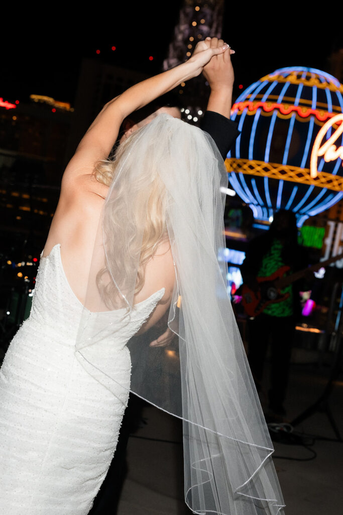 Bride dancing with veil flowing against the skyline.