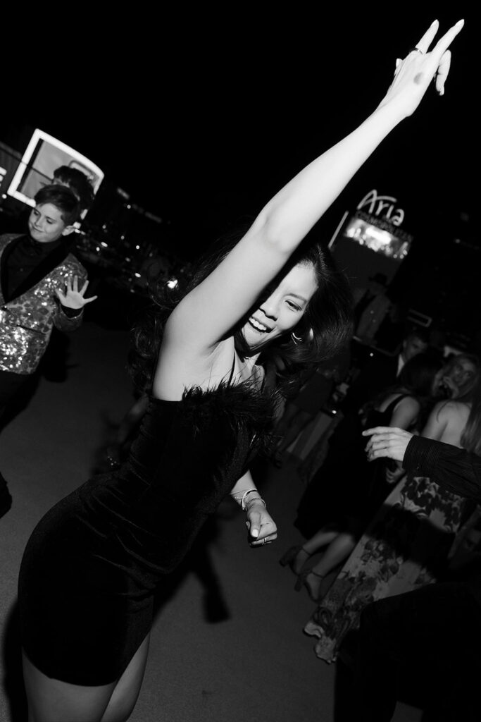 Woman dancing with her arm raised during a lively rooftop wedding celebration overlooking the Las Vegas Strip.