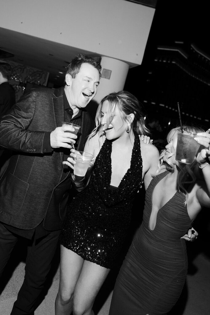 Guests celebrating cocktails during a Cosmopolitan rooftop wedding reception at night.