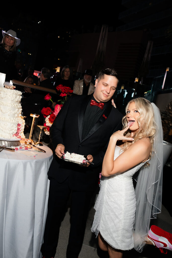 Bride playfully posing beside the cake during her Cosmopolitan wedding reception in Las Vegas.