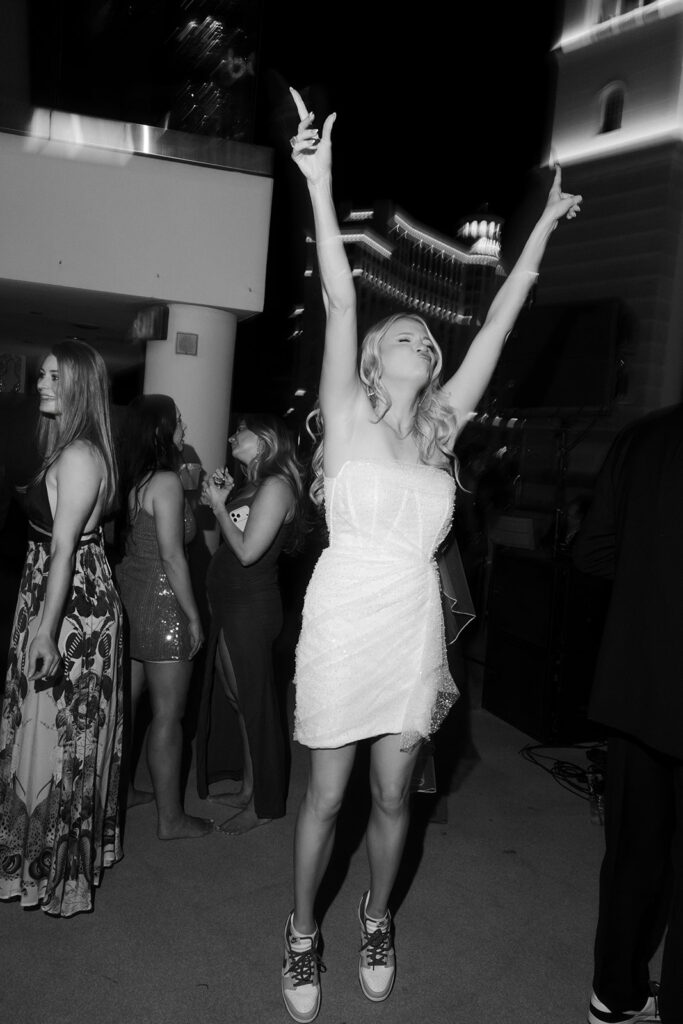 Black and white photo of a bride dancing with her hands in the air.