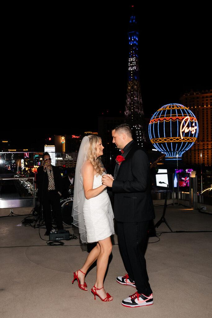 Bride and groom celebrating together with Strip views behind them during a rooftop Cosmopolitan wedding reception.