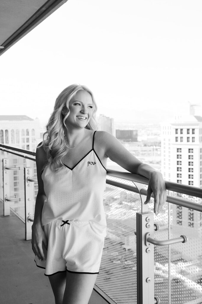 Black and white portrait of the bride leaning on a balcony railing during her Cosmopolitan wedding in Las Vegas.