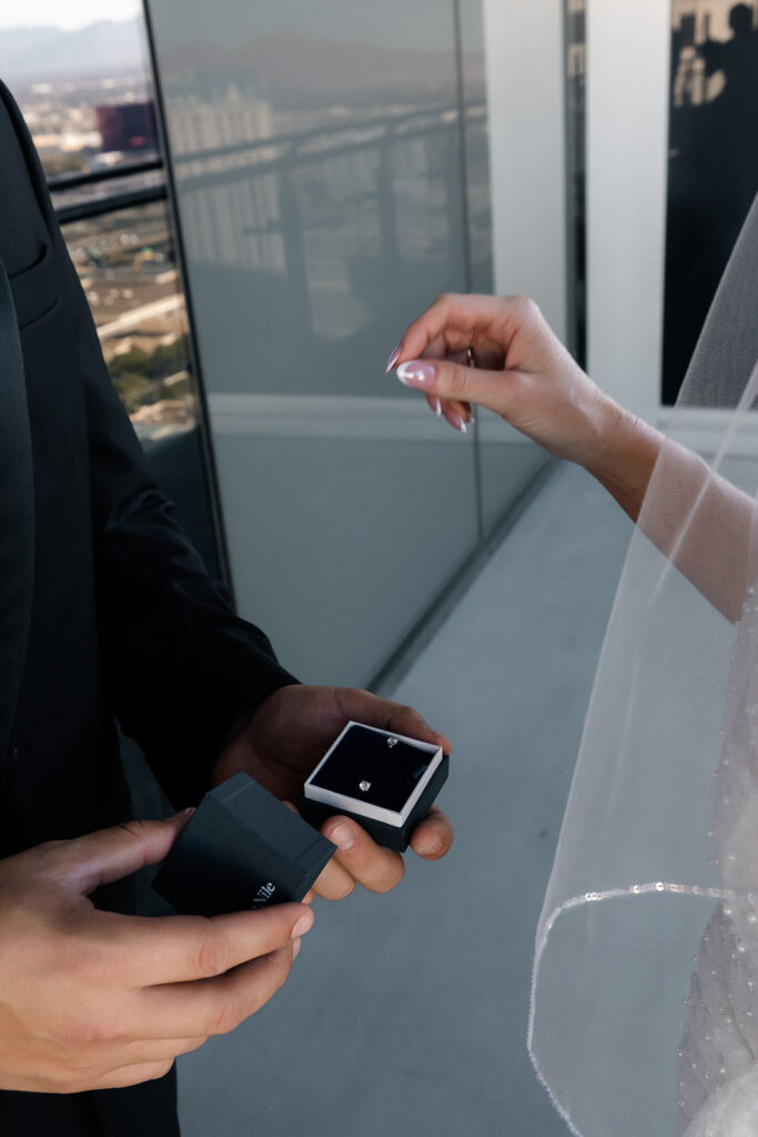 Close-up photo of the groom holding an open ring box as the bride reaches out during a Cosmopolitan wedding in Las Vegas.