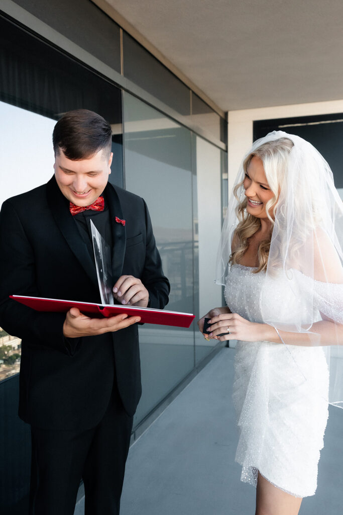 Bride and groom smiling while looking at a boudoir gift book given to the groom from the bride.