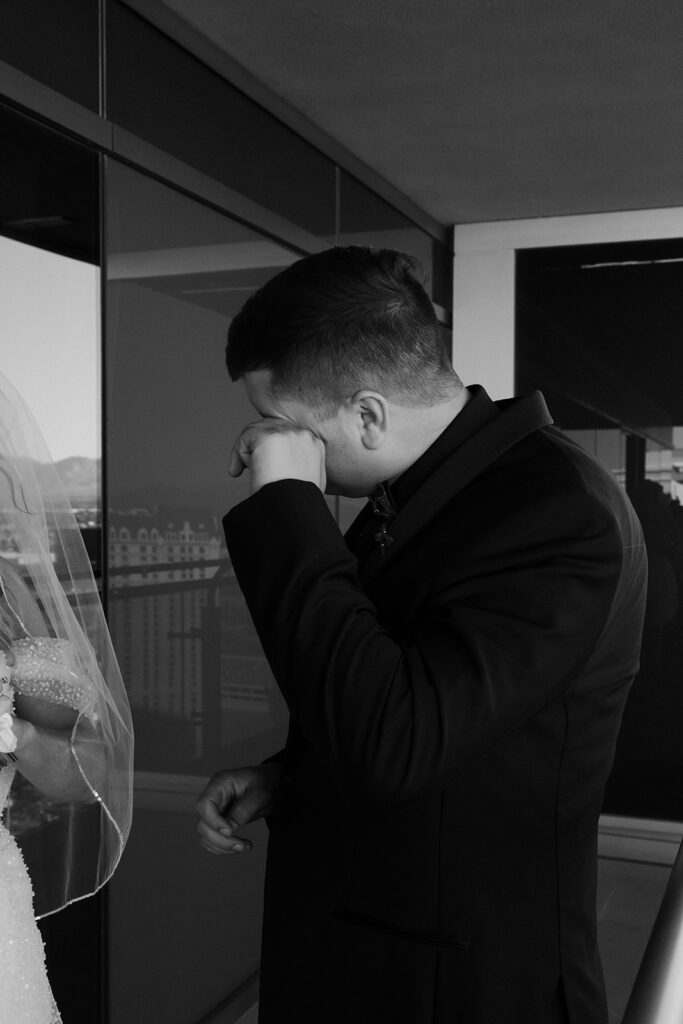 Black and white photo of the groom wiping away tears during the first look at a Cosmopolitan wedding in Las Vegas.