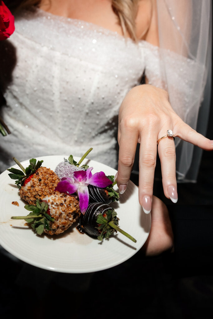 Close-up of the bride’s engagement ring as she reaches for plated desserts during a Cosmopolitan wedding in Las Vegas.