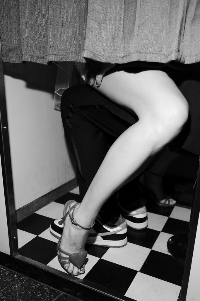 Black and white photo of the bride’s legs and heels next to the groom’s sneakers in a photobooth in Las Vegas.