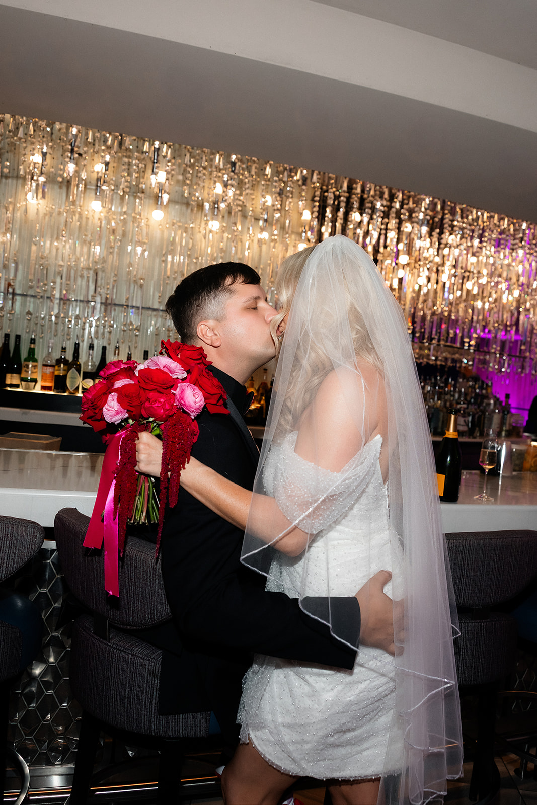 Bride and groom share a kiss at The Chandelier Bar inside The Cosmopolitan during their Las Vegas wedding celebration.