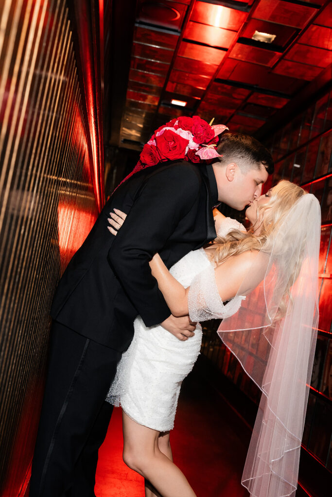 Bride and groom kissing in a red-lit hallway at The Cosmopolitan during editorial Las Vegas wedding portraits.