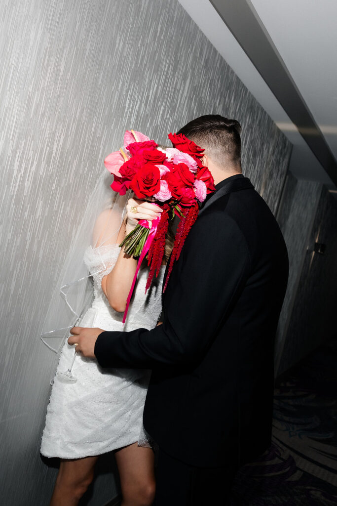 Bride holds her bouquet up between her and the groom during a fun portrait moment at a Cosmopolitan wedding in Las Vegas.