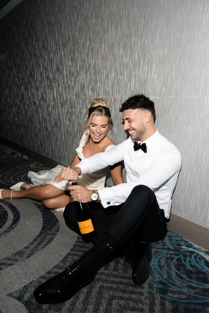 Flash photo of a bride and groom sitting in the hallway at The Cosmopolitan with champagne for their classy elopement in Las Vegas. 