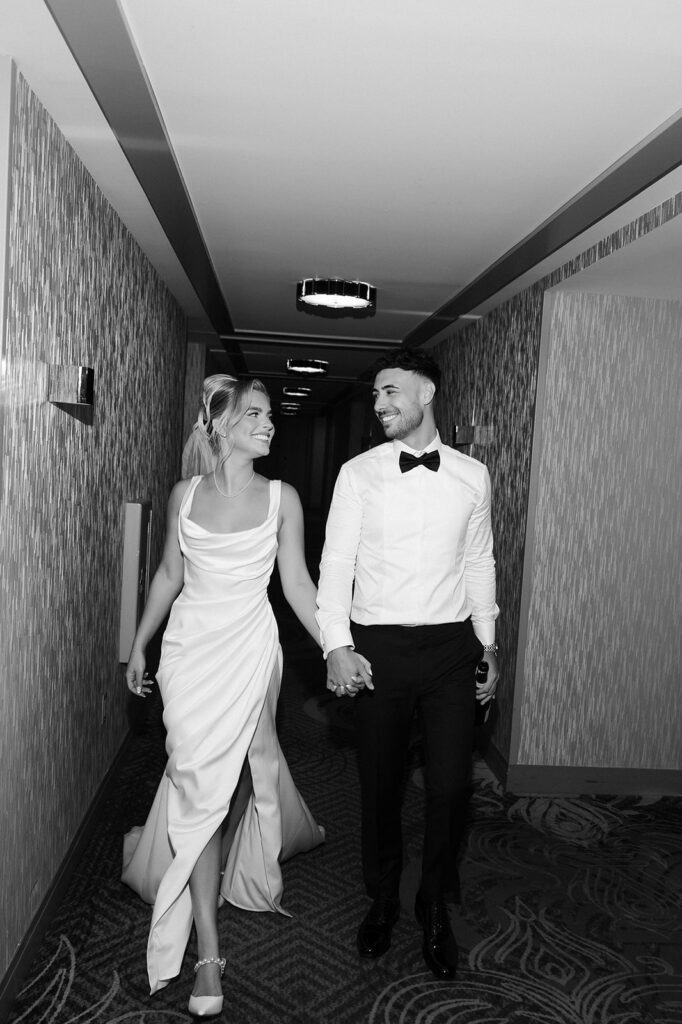 Black and white photo of a bride and groom walking down the hallway during their classy elopement in Vegas.