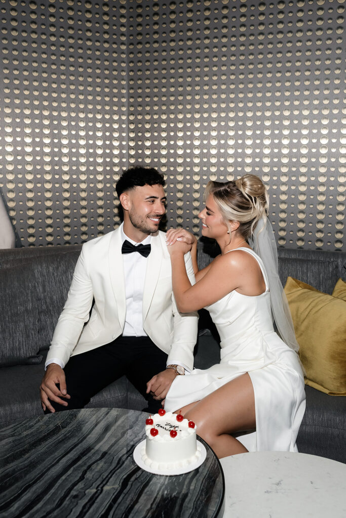 Bride and groom sitting together in their suite at The Cosmopolitan with an elopement cake on the table.