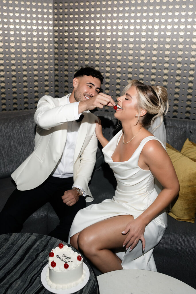 Groom feeding the bride a cherry off of their elopement cake.