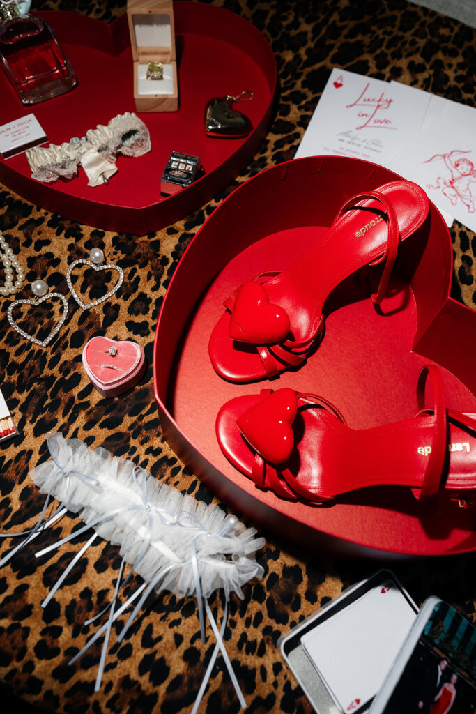 Wedding detail flat lay featuring red heels, rings, invitations, and accessories styled for a Cosmopolitan wedding in Las Vegas.