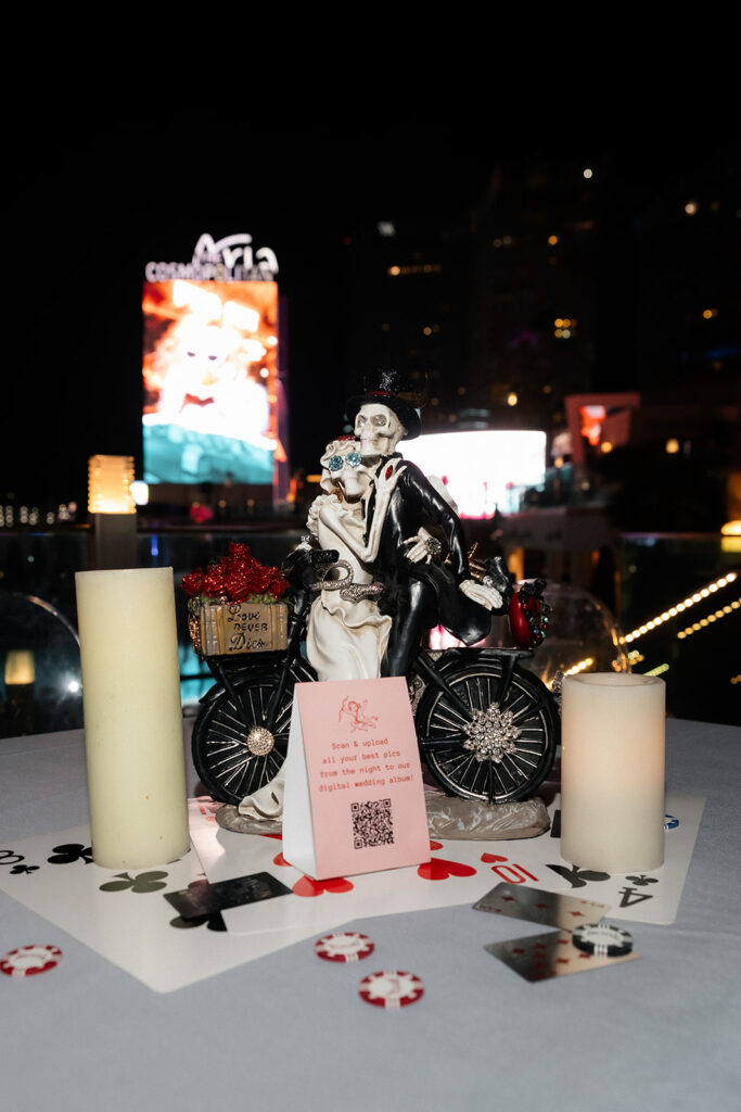 Skeleton cake topper and playing card details displayed on a reception table during a rooftop Cosmopolitan wedding on the Boulevard Pool Deck in Las Vegas.