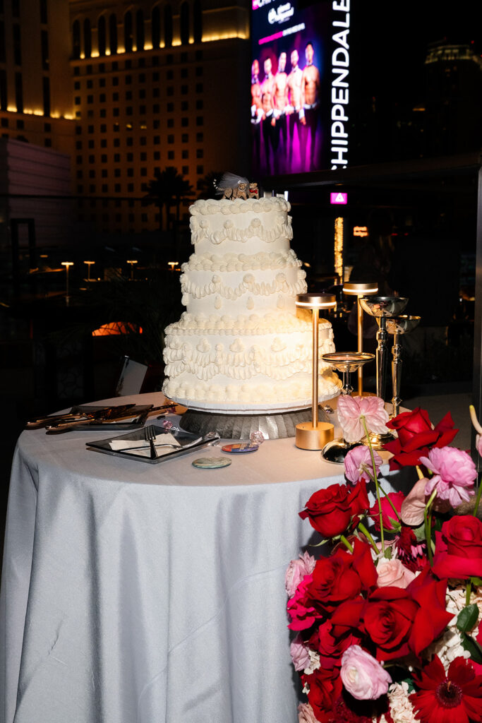 Wedding cake and florals set up on the Boulevard Pool Deck with Las Vegas Strip views during a rooftop Cosmopolitan wedding.