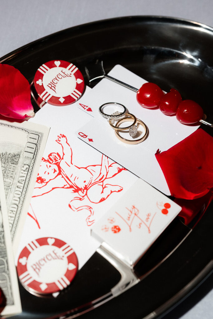 Las Vegas wedding details with cherries, rings, playing cards, poker chips and money.