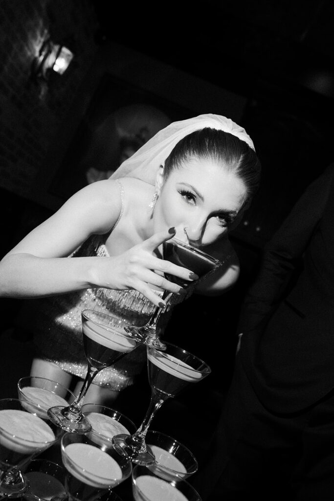 Bride sipping an espresso martini from a stacked cocktail tower during a Commonwealth Las Vegas wedding reception.