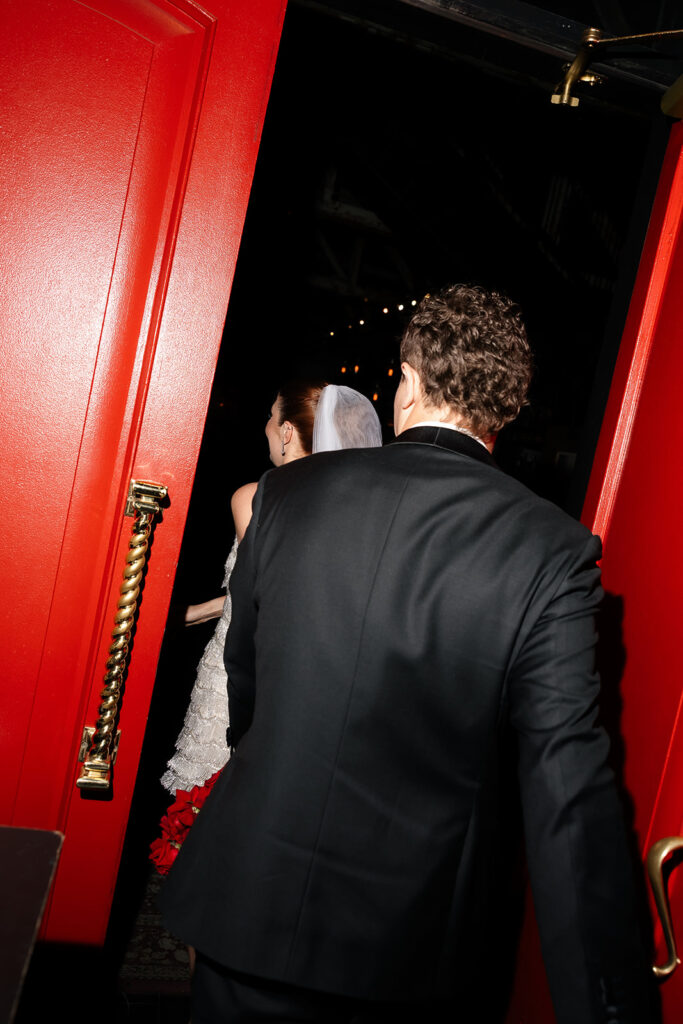 Bride and groom entering Commonwealth through red doors after their Las Vegas wedding ceremony.