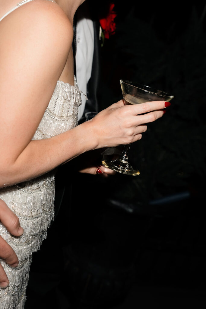 Close-up of the bride holding an espresso martini while standing beside the groom during their rooftop reception at Commonwealth.