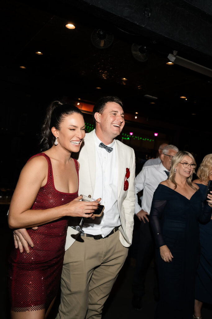 Wedding guests laughing and holding drinks during a lively Commonwealth Las Vegas wedding reception.