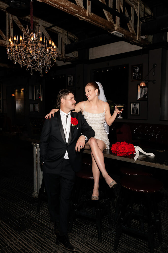 Bride and groom sitting together at the bar inside Commonwealth during their Las Vegas wedding reception.
