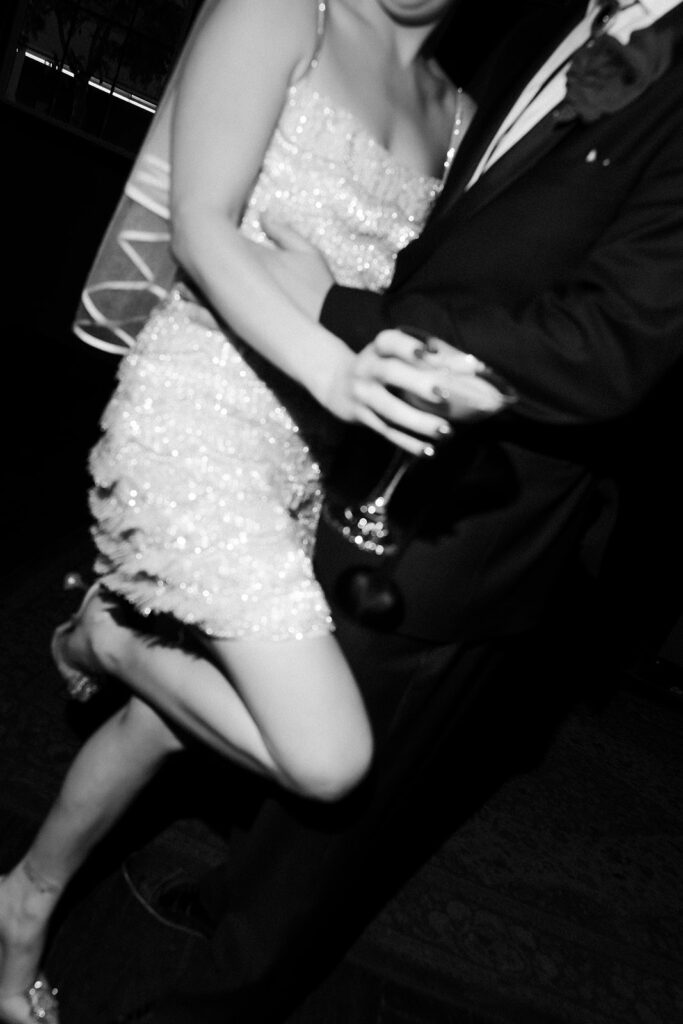 Black and white photo of a bride and groom posing while the bride holds an espresso martini at Commonwealth Las Vegas.