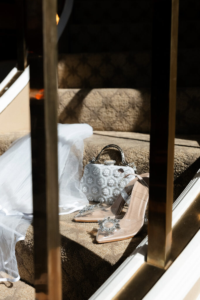 Bridal shoes, veil, and beaded handbag styled on the staircase during getting ready at the Golden Nugget in Las Vegas.