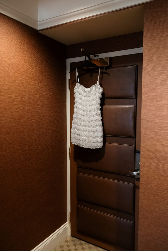 A short beaded wedding dress hanging in the Golden Nugget Spa & Suite during getting ready in Las Vegas.