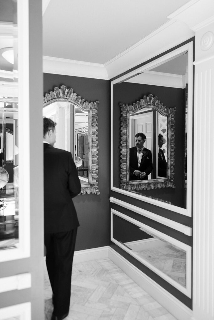 Black and white portrait of a groom adjusting his suit in a hallway at the Golden Nugget while getting ready.