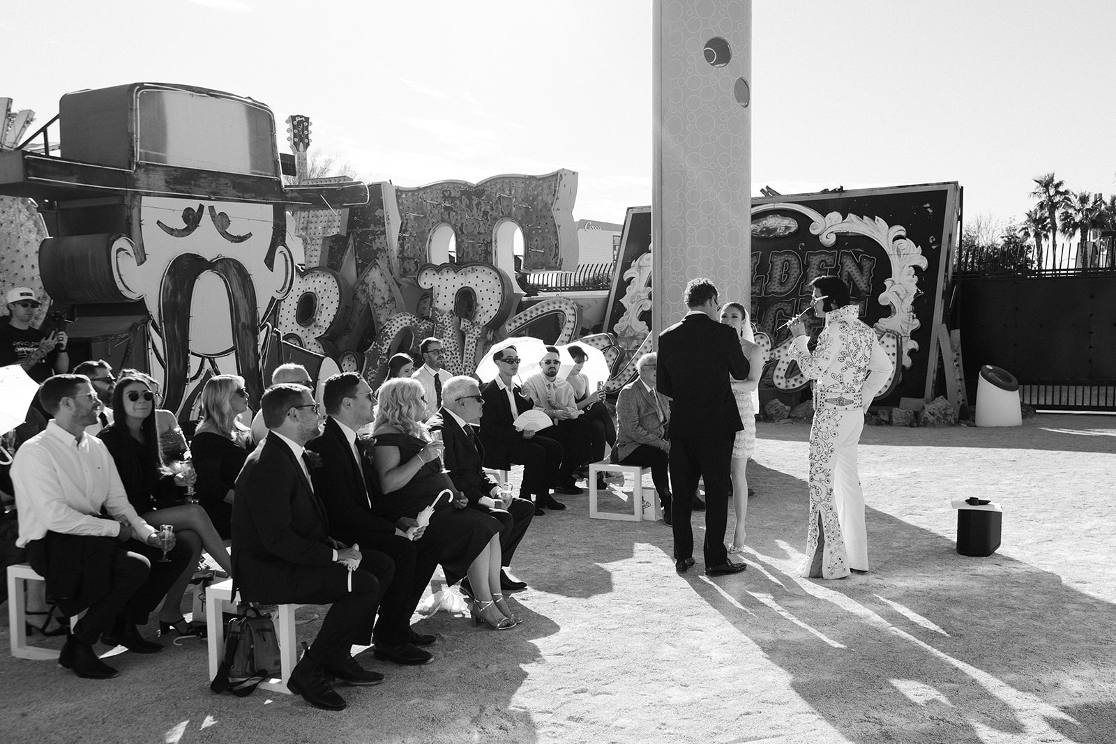Wide view of a Neon Museum wedding ceremony with guests seated beneath historic Las Vegas signs.