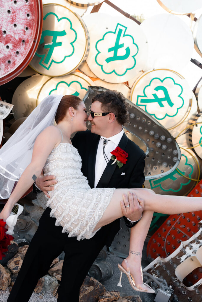 Bride and groom kissing in front of vintage neon signs at the Neon Museum in Las Vegas.