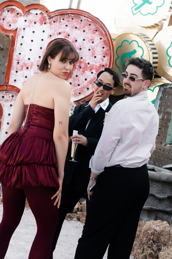 Group of wedding guests posing playfully in front of vintage neon signage at the Neon Museum.