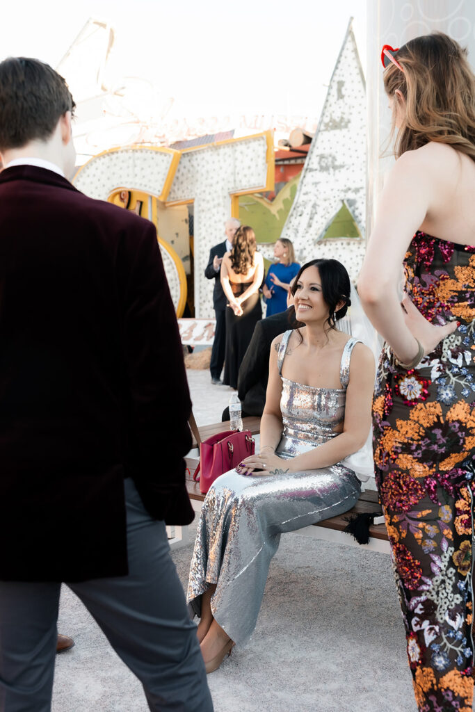 Bride sitting at the Neon Museum and mingling with guests during her Las Vegas wedding.