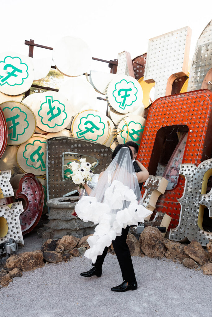 Groom lifting and twirling his bride during their Neon Museum wedding photos in Las Vegas.