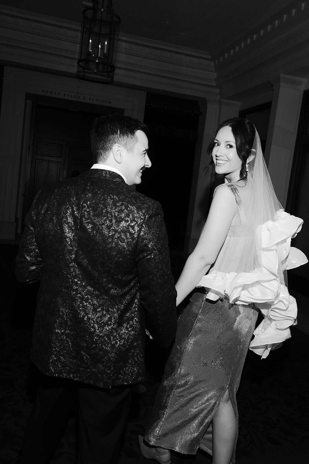 Black and white photo of a bride and groom walking away from the camera.