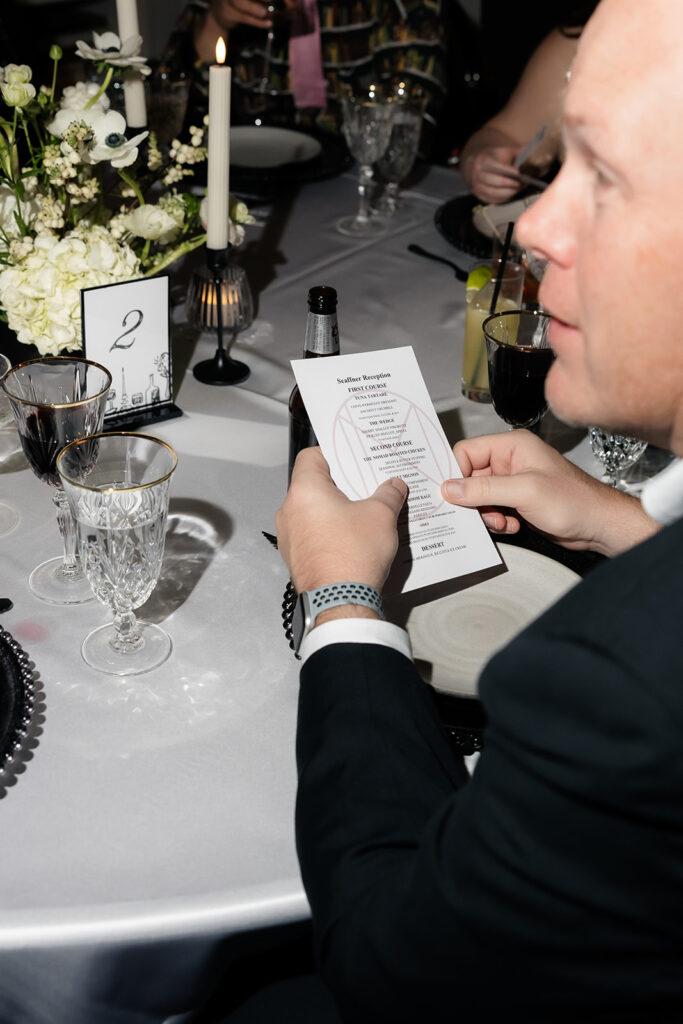 Guest reading the dinner menu at a candlelit table during an intimate Las Vegas micro wedding reception at NoMad Library.